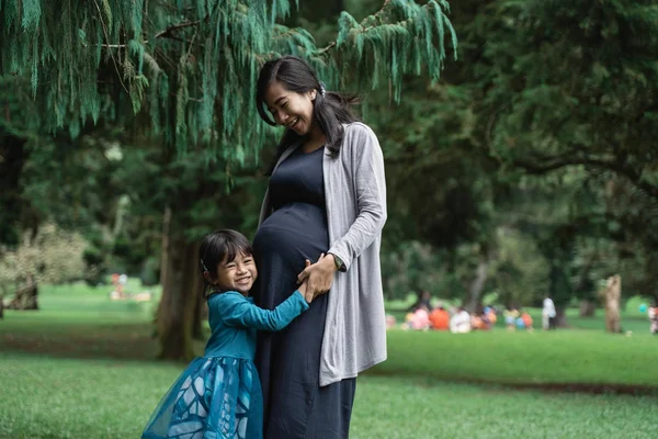 Petite fille étreint sa mère enceinte — Photo