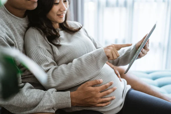 Marido y mujer utilizan pestañas para ver la información sobre el embarazo —  Fotos de Stock