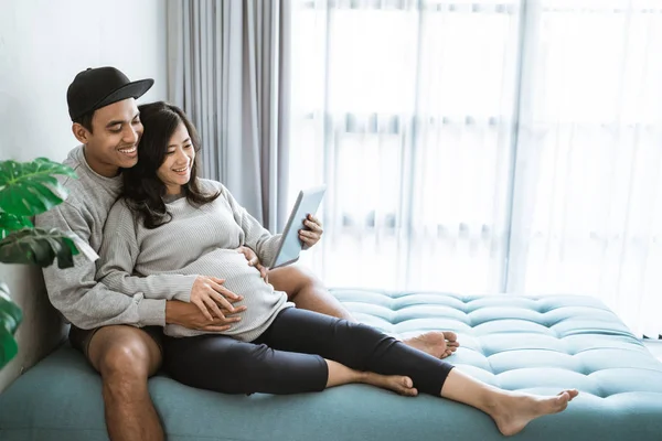 Marido y mujer utilizan pestañas para ver la información sobre el embarazo — Foto de Stock