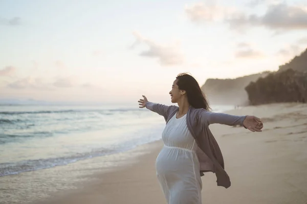 Gelukkige zwangere vrouwen staan op het strand — Stockfoto