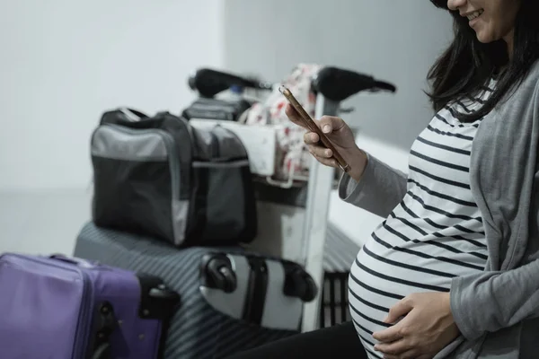 Mujeres asiáticas embarazadas sonríen mientras miran sus teléfonos celulares — Foto de Stock