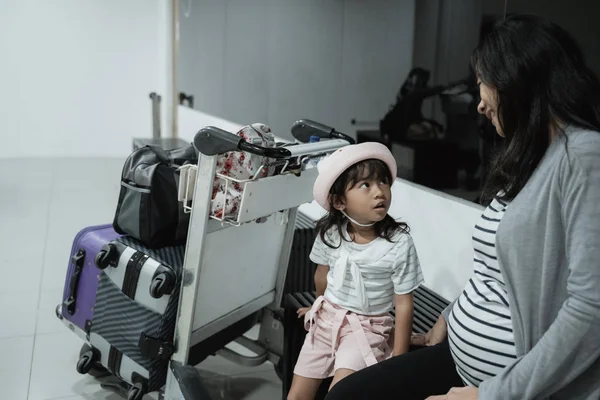 Terhes ázsiai nő és lánya élvezi csevegni a váróteremben repülőtéren — Stock Fotó