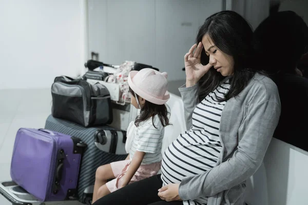 Беременные женщины с головной болью и его дочь, когда сидят вместе — стоковое фото