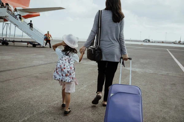 Маленька дівчинка і мати тримає руки йдуть до літака — стокове фото