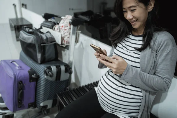 Беременные азиатки улыбаются, глядя на свои мобильники. — стоковое фото