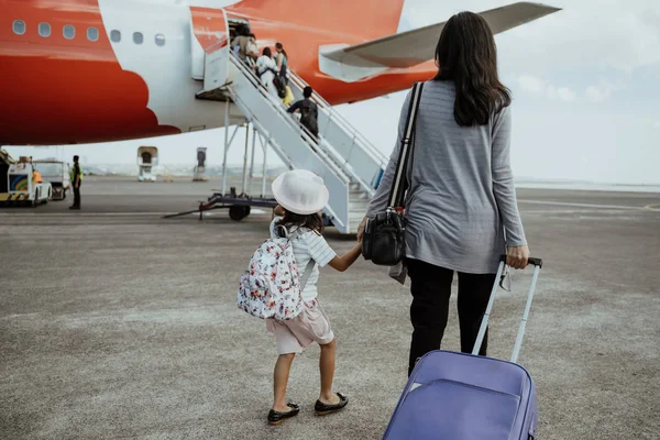 Маленька дівчинка і мати тримає руки йдуть до літака — стокове фото