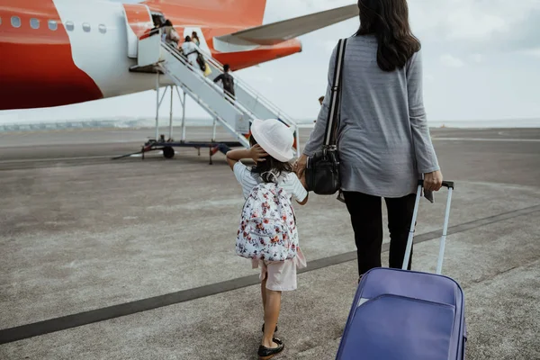 Мати і дочка приєднуються руки, ходячи з валізою — стокове фото