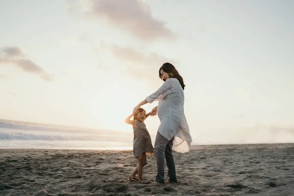Junge Mutter spielt mit ihrem kleinen Mädchen am Meer — Stockfoto