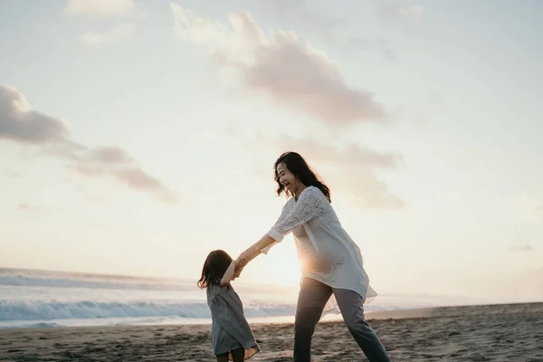 Jovem bela mulher grávida com sua filhinha fofa brincando na praia — Fotografia de Stock