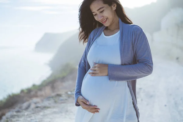 Mooie zwangere vrouw die op het strand staat — Stockfoto