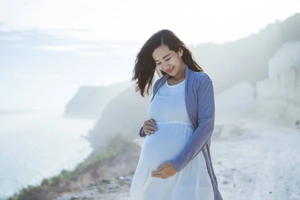 Pregnant mother stands next to a cliff — Stock Photo, Image