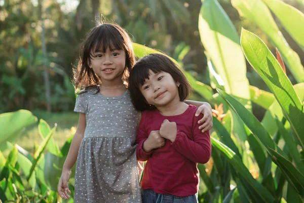 Two little girls stand embrace while in the park — Stock Photo, Image