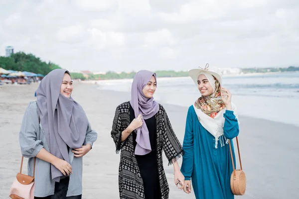 Tre beslöjade kvinnor njuta av en semester på stranden — Stockfoto