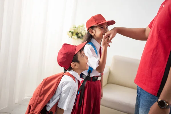 student kiss his parents hand before going to school