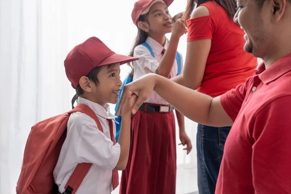 student kiss his parents hand before going to school