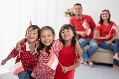 Endonezyalı aile beyaz arka plan üzerinde Endonezya bayrağı tutarak