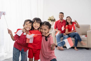 Endonezyalı aile beyaz arka plan üzerinde Endonezya bayrağı tutarak