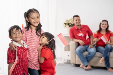 Endonezyalı aile beyaz arka plan üzerinde Endonezya bayrağı tutarak