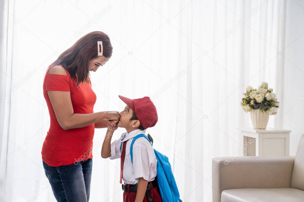 kid kissing mothers hand while shaking hand