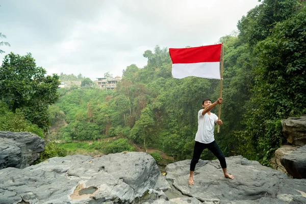 Uomo con bandiera indonesiana dell'indonesia in cima alla montagna — Foto Stock