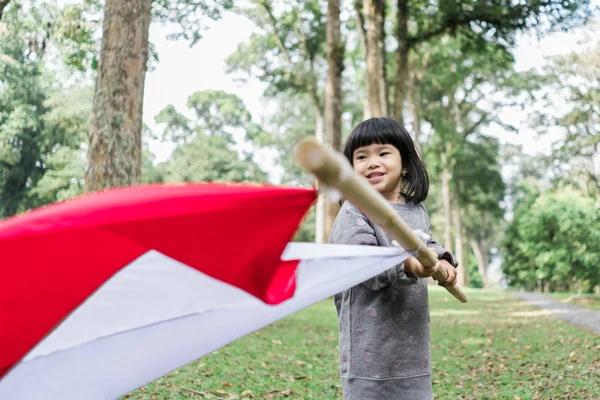 Linda niña sosteniendo gran palo de bandera de la nación con sonrisa —  Fotos de Stock