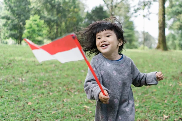Asiatique petite fille tenant un bâton de drapeau indonésien avec dents — Photo