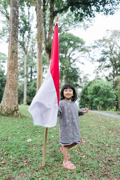 Fille indonésienne tenant bâton de bambou avec grand drapeau — Photo