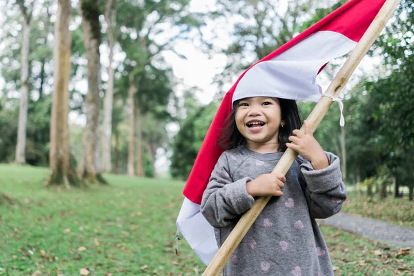 Indonesiska flicka som innehar bambu pinne med stor flagga — Stockfoto