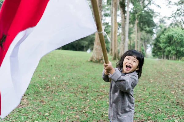 Indonesiska flicka som innehar bambu pinne med stor flagga — Stockfoto
