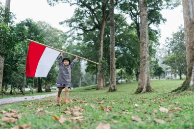 Endonezyalı kız büyük bayrak ile bambu sopa tutan