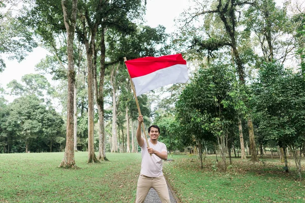 Pemuda Indonesia memegang tongkat bambu dengan bendera besar — Stok Foto