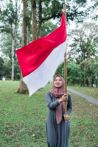 アジアのベールに包まれた女性はインドネシアの旗を羽ばたかせる — ストック写真