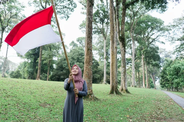 Perempuan hijab Indonesia memegang tongkat bambu dengan bendera besar — Stok Foto