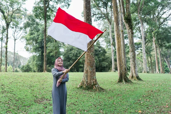 Ásia velado mulher batendo indonésio bandeira — Fotografia de Stock