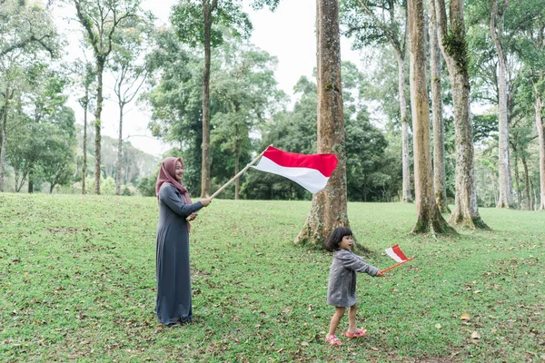 Perempuan hijab Indonesia memegang tongkat bambu dengan bendera besar — Stok Foto
