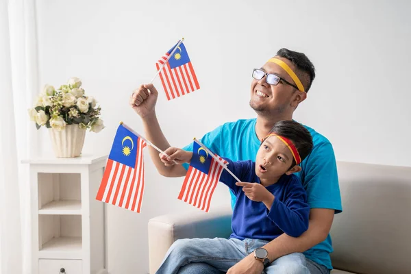 Ayah dan anak memegang bendera malaysian bersama-sama saat menonton pertandingan sepak bola — Stok Foto