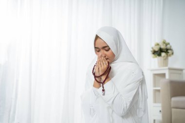 El-Kuran ve tespih ile dua eden Asyalı genç kadın.