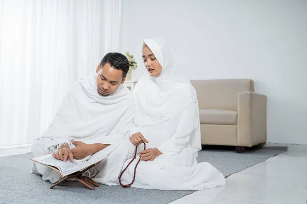 Муж и жена азиата молятся вместе с Кораном и тасбией — стоковое фото