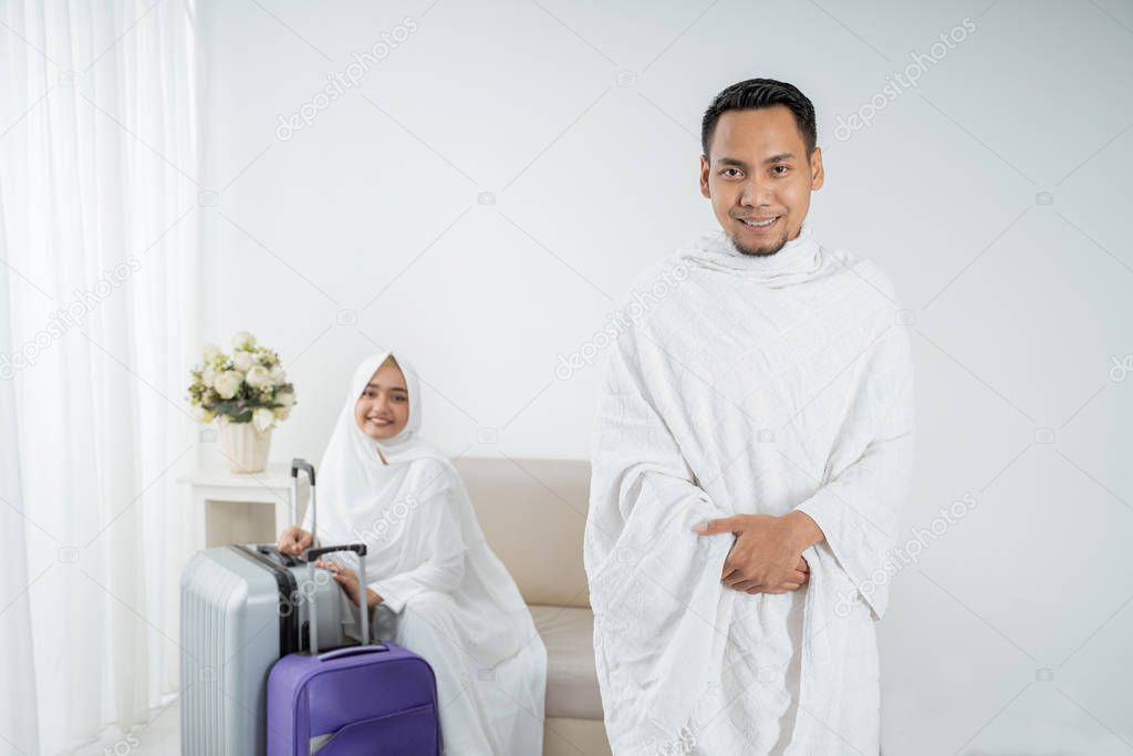 muslim young man standing in front of his wife before umrah