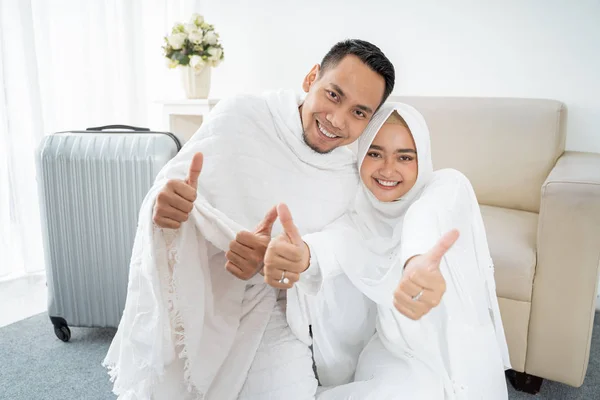Muslimisches Paar sitzt in weißer Tracht mit erhobenen Händen — Stockfoto