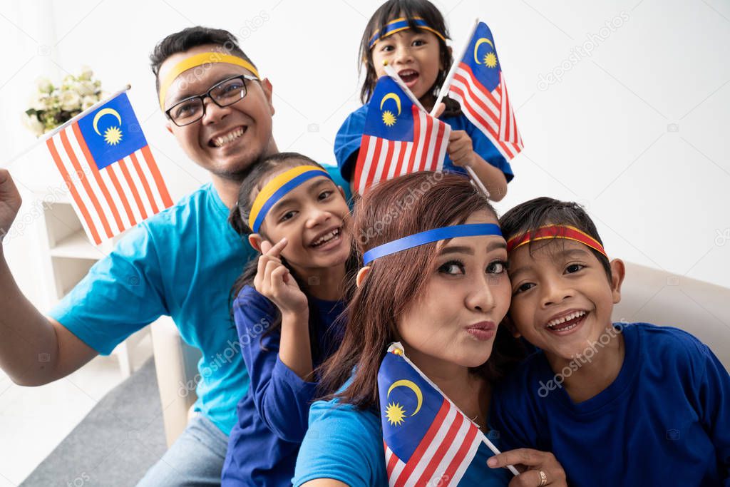 family with malaysian flag take selfie together