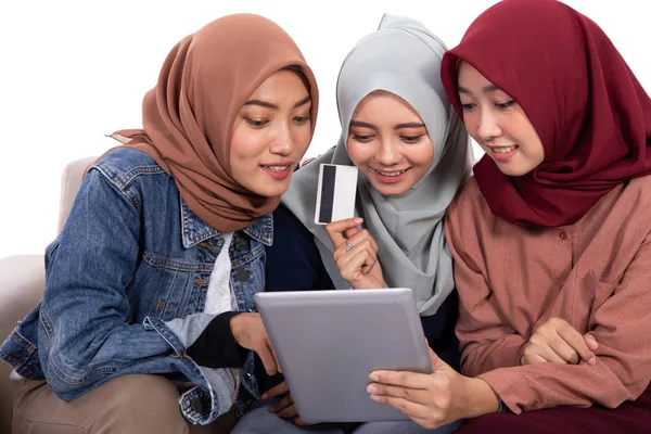 Vriendschap van drie gesluierde vrouwen tijdens het ontspannen zitten en het houden van creditcard om te kopen in een online winkel — Stockfoto