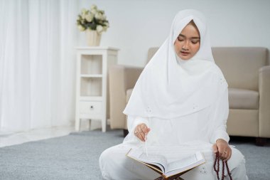 El-Kuran ve tespih ile dua eden Asyalı genç kadın.