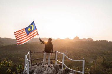 man with malaysian flag of malaysia on top of the mountain clipart