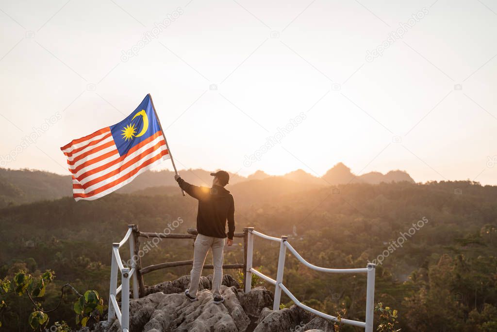 man with malaysian flag of malaysia on top of the mountain