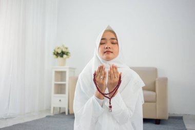 Geleneksel beyaz giysiler içinde dua eden Müslüman genç kadın.