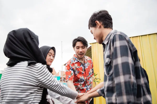 Asiatische junge Leute, die ihre Hände zusammenlegen — Stockfoto