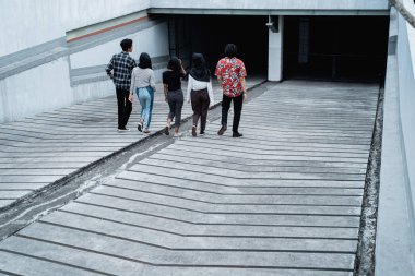 Genç arkadaşların arka görünümü birlikte yürüyüp gitti