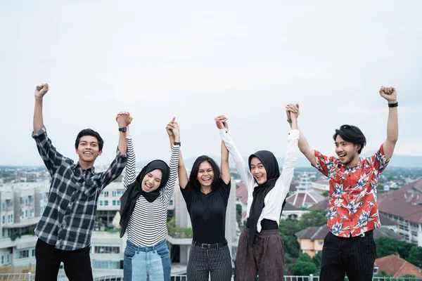 Young people hanging out and raise hand on the building rooftop