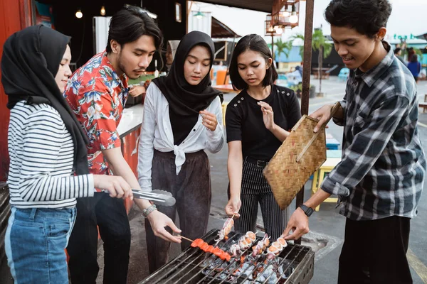 Grupo de amigos grelhar comida com um espeto — Fotografia de Stock